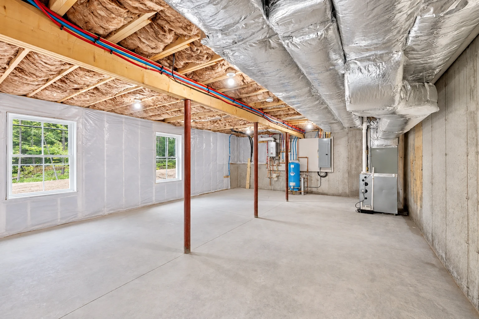 Basement with insulated ceiling joists, white-covered walls, exposed concrete floor, and large silver ducts overhead.